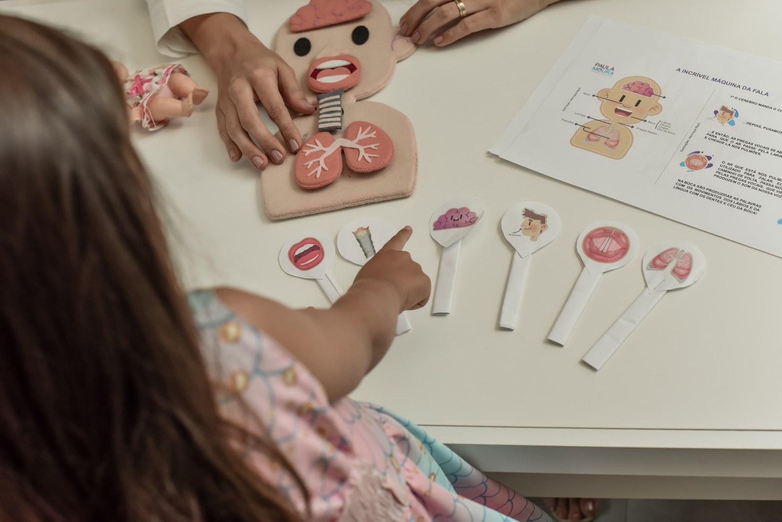Criança e Paula Moura brincando com os cartões da máquina da fala
